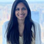 smiling woman looks at camera high above central park in the window behind her